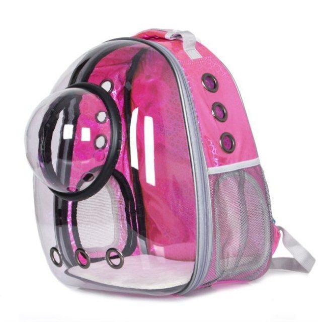 The Clear Cat and Dog Carrier Backpack is a pink, transparent pet carrier with a bubble window and ventilation holes, offering stylish breathability and secure comfort for carrying small animals.